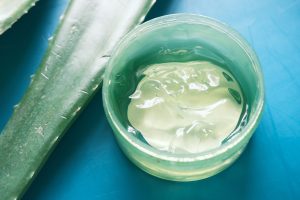 Fresh aloe vera sliced and liquid gel in plastic container on green background Fresh aloe vera sliced and liquid gel in plastic container on green background .